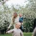 A joyful family enjoys a playful day outdoors amidst blossoming trees in spring.