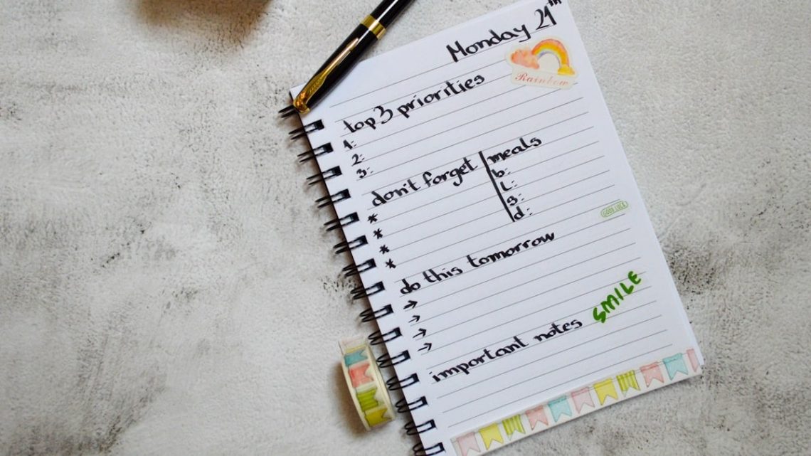 Flatlay of a planner with a pen, candle, stickers and washitape